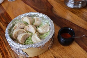 集落の食堂でモモをいただく。素朴な味わいにホッとする。右の赤い香辛料はとてつもなく辛かった。